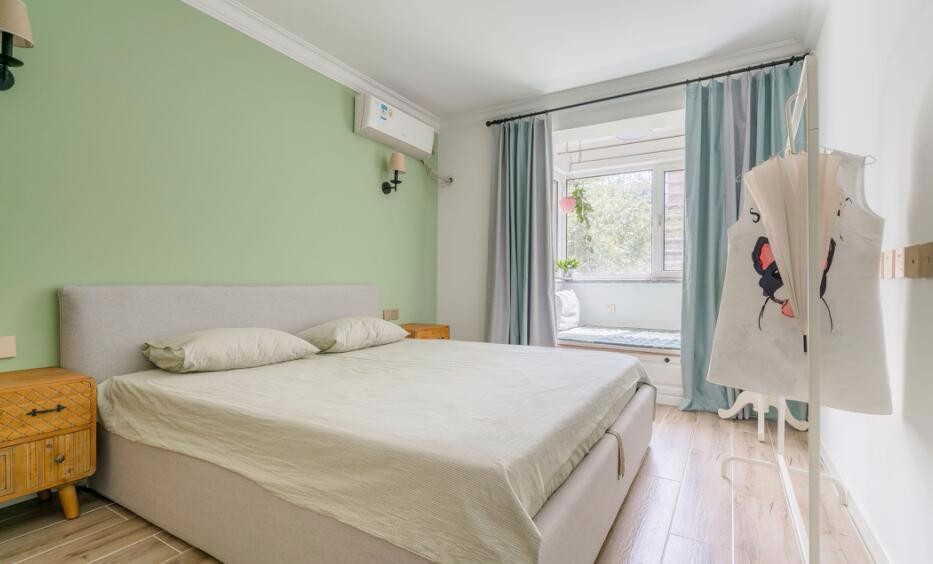 卧室墙面粉刷整面浅豆绿色,搭配灰色靠背的双人床#卧室#床