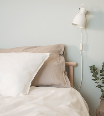 天然亚麻枕套和被套映衬着卧室的浅绿色墙壁