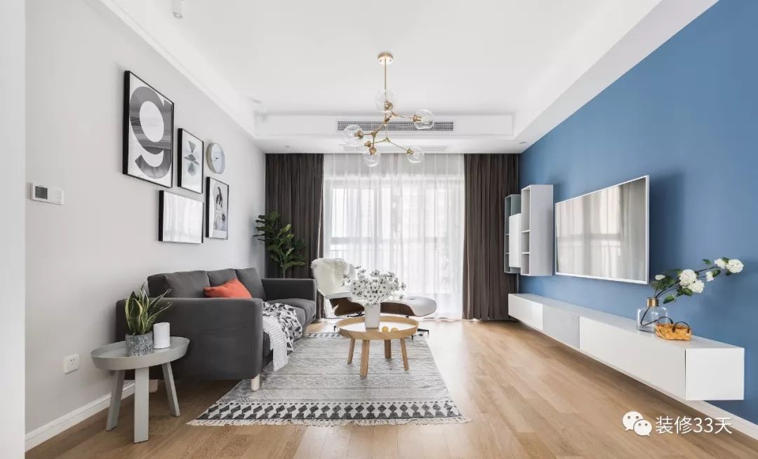 客厅地面通铺木色地 板,墙面采用蓝灰两种色调,视觉上具有层次感